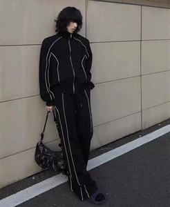 Détail d'un survêtement noir avec passepoil blanc contrasté et design à col montant