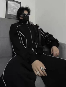 Détail d'un survêtement techwear noir avec col montant et surpiqûres blanches contrastées