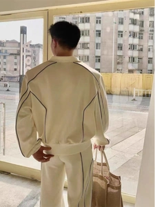 Vue arrière d'un survêtement beige avec rayures bleues sur la veste et pantalon large