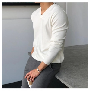 Detailansicht eines weißen Herren-Strickpullovers mit V-Ausschnitt und dunkelgrauer Anzughose