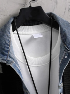 Detailansicht der Denim-Patchwork-Nähte und des schwarzen Strickstoffs der Herrenstrickjacke