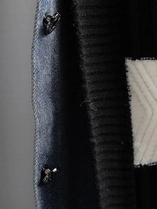 Detail der Strickjacke aus Denim und schwarzem Strick mit Metalldruckknöpfen