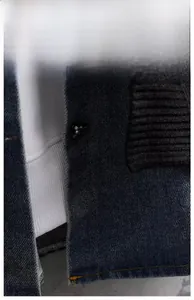 Detail aus dunkelblauem Denim-Köperstoff mit schwarzem Strickkragen und Metalldruckknopf