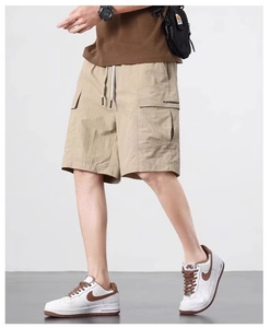Detail of khaki cargo shorts showing elastic drawstring waist and functional side flap pocket