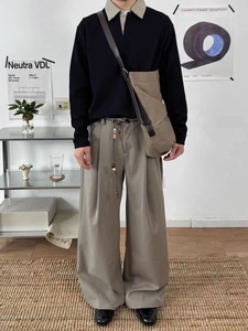 Dettaglio polo da uomo e pantaloni larghi con accessorio in vita con perline
