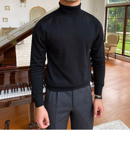 Detail eines schmal geschnittenen schwarzen Rollkragenpullovers mit grauer Hose und Uhr