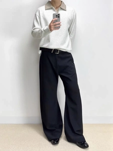 Dettaglio polo grigia con colletto a quadri e pantaloni neri larghi stile casual