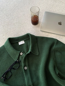 Flachbild einer dunkelblauen Strickjacke mit Strukturstoff und dunklen Knöpfen auf Tisch