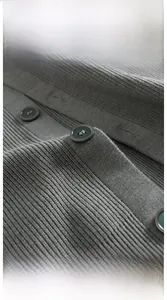 Gros plan détaillé du cardigan gris en maille avec boutons vert foncé et texture côtelée