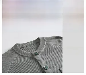 Détail de l'encolure d'un cardigan gris en maille avec boutons vert foncé et texture côtelée