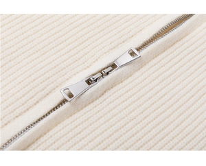 Λεπτομέρεια από ασημί διπλό φερμουάρ σε off-white πλεκτό πουλόβερ με ραβδώσεις