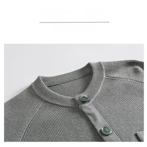 Détail du col d'un cardigan gris en maille côtelée avec boutons verts et manches raglan