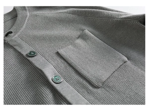 Détail du cardigan gris montrant la texture côtelée et le bouton vert sur la poche