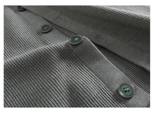 Détail macro du cardigan en tricot gris foncé montrant la maille et les boutons