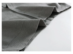 Gros plan sur le tissu gris d'un gilet en maille avec bouton rond et texture fine