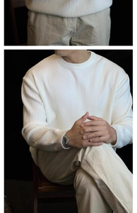 Detailed close-up of men's white crewneck knit sweater with vertical ribbed texture and cuffs