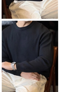 Detail of men's black ribbed knit sweater with a classic crew neck and a slim fit design