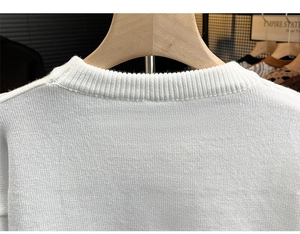 Détail d'un pull blanc à col rond montrant la texture du tricot et les finitions côtelées