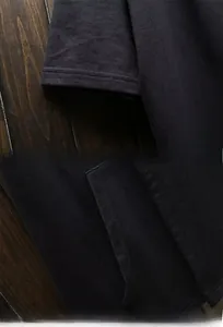 Macro detail of dark hooded cloak showing sleeve stitching and side pocket design