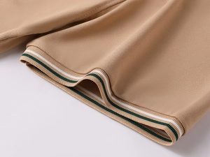 Detail of khaki polo shirt cuff with breathable pique texture and striped ribbing