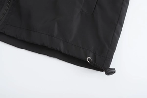 Detail of adjustable hem with elastic drawstring and toggle on black hooded jacket