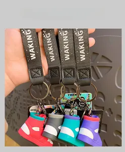 Hand holding colorful sneaker keychains with WAKING wrist straps in four vibrant colors