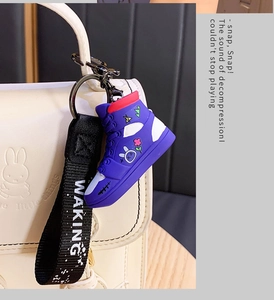 Detail of a purple sneaker keychain with miffy rabbit pattern on a white backpack