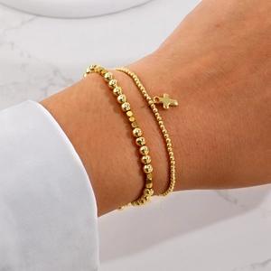 Fashionable layered gold beaded bracelet set featuring a minimalist cross pendant design