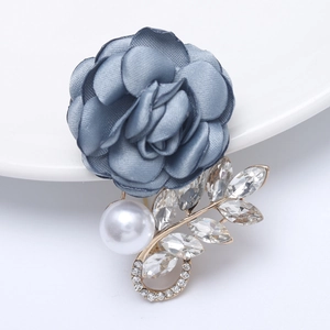Detailed view of dark blue fabric flower brooch with white pearl and marquise rhinestones