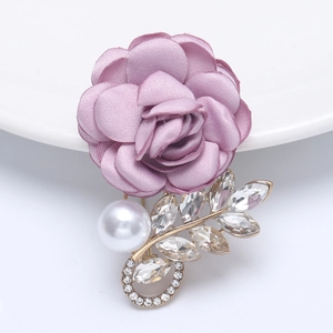 Detailed view of purple silk flower brooch with white pearl and rhinestone gold leaf accents