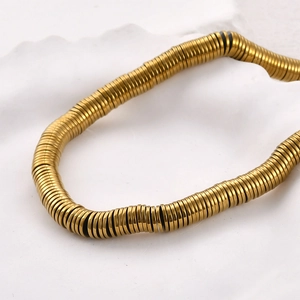 Makroaufnahme goldener flacher Scheibenperlen auf weißem Tablett für DIY-Schmuck