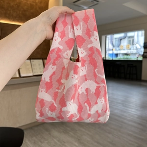 Close-up of knit tote bag showing soft pink and white cat pattern texture and handle