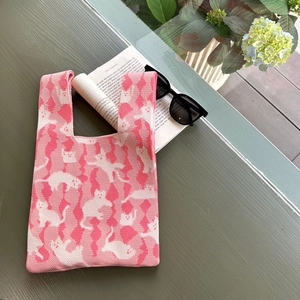 Detail of pink knit tote bag showing cat silhouettes and soft woven texture