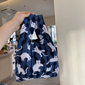 Detail of the thick camouflage knit fabric and white cat pattern on a wrist tote bag