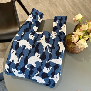 Knitted tote bag with white cat pattern and blue geometric design on gray table