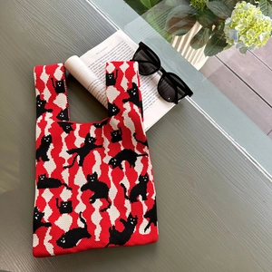 Close-up of knit tote bag featuring black cat silhouettes on red and white diamond pattern