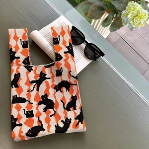 Close-up of knit tote bag featuring a black cat silhouette and orange geometric patterns