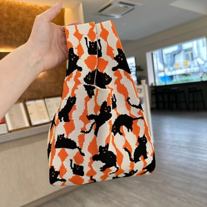 Close-up of a thick knit tote bag featuring black cat silhouettes on orange diamond patterns