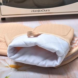 Orange silicone oven mitts with quilted cotton lining and hanging loop for heat protection