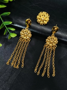 Macro detail of 24k gold plated jewelry set with floral ring and long tassel earrings