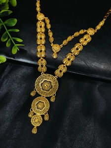 Detailed macro view of 24k gold necklace with intricate filigree and heart shaped links