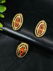 Detailed view of 24k gold-plated jewelry set with red rhinestones on black background