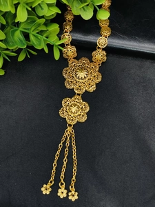 Detail of 24k gold floral filigree necklace with intricate cutouts and long chain tassels