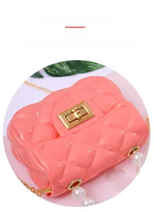 Detailed close-up of pink jelly cross-body bag with gold twist lock and pearl accents