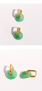 Macro detail of U-shaped gold earrings with green aventurine stone donuts and shadow play