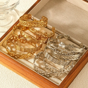 Detailed set of gold and silver stainless steel bangles showcased in a wooden jewelry box