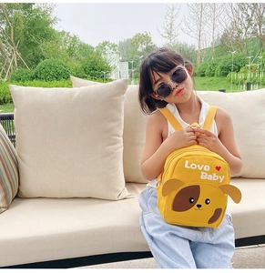 Close-up of a yellow canvas toddler backpack with cute dog pattern and Love Baby text
