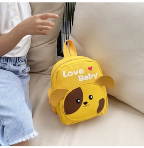 Detail shot of a yellow cartoon dog backpack for kids on a sofa with Love Baby print