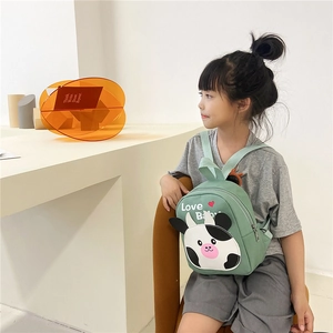 Detail of light green canvas backpack with cow pattern and adjustable shoulder straps