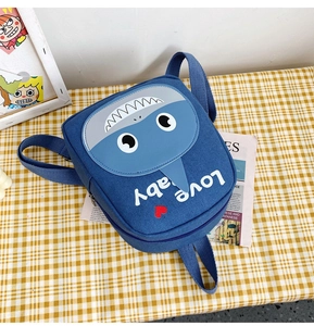 Detail view of a blue canvas toddler backpack with a 3D cartoon shark design and soft straps